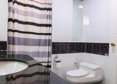 Modern bathroom with striped shower curtain and mosaic tile accents