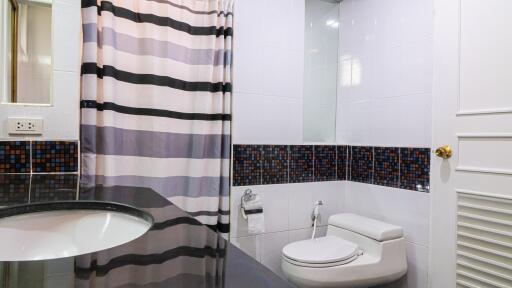 Modern bathroom with striped shower curtain and mosaic tile accents