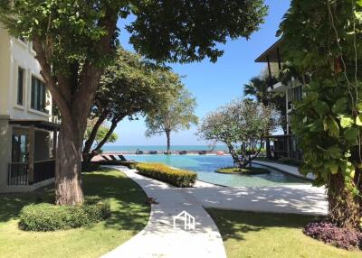 View of the pool area with trees and an ocean in the background