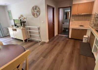 Open-concept living area with dining table, kitchenette, and wood flooring