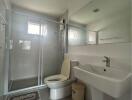 Modern bathroom with glass shower, sink, and toilet