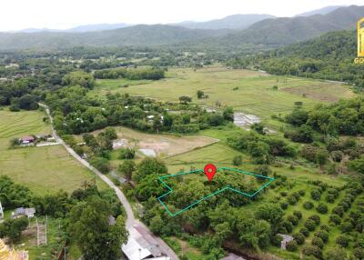 Aerial view of a vast rural land with greenery, hills in the background, and a property marked with a pin.