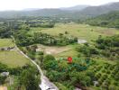 Aerial view of a vast rural land with greenery, hills in the background, and a property marked with a pin.