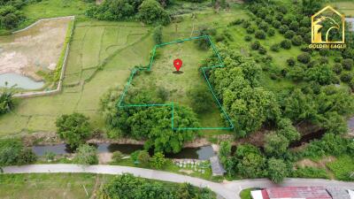 Aerial view of a plot of land marked within a larger green landscape with trees and fields