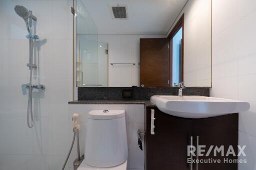 Modern bathroom with a white sink, toilet, and shower area