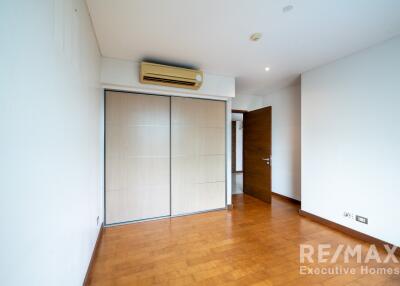 Bedroom with wooden flooring, built-in wardrobe, and air conditioning unit