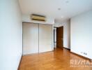 Bedroom with wooden flooring, built-in wardrobe, and air conditioning unit