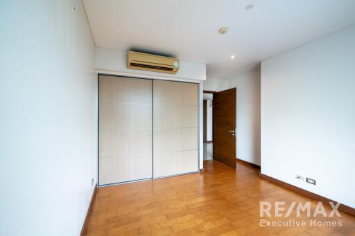 Bedroom with wooden flooring, built-in wardrobe, and air conditioning unit