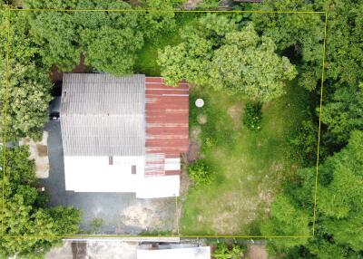 Aerial view of a building with a metal roof surrounded by trees and greenery