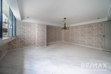 Spacious living room with large windows, chandelier, and marble tiled floor