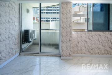 Modern living area with marble-patterned walls and floors, featuring a balcony with a city view.