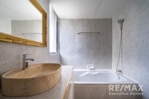 Modern bathroom with a marble sink, bathtub, wall-mounted shower, and large window