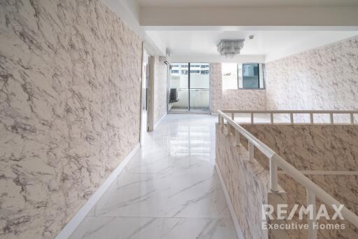 Second-floor hallway with marble patterned walls and natural light