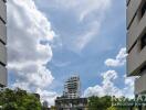 View of a modern cityscape with buildings and trees under a partly cloudy sky