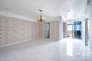 Spacious and brightly lit living area with marble flooring and modern chandelier