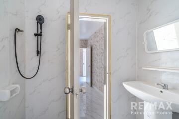 Modern bathroom with white marble walls, sink, and shower