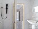 Modern bathroom with white marble walls, sink, and shower