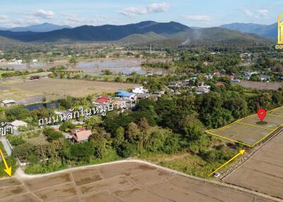 Aerial view of village by fields and mountains