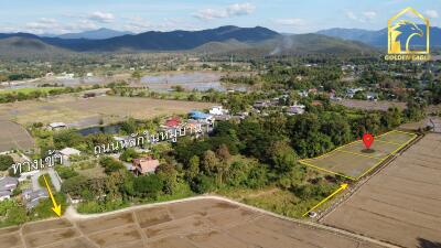 Aerial view of village by fields and mountains