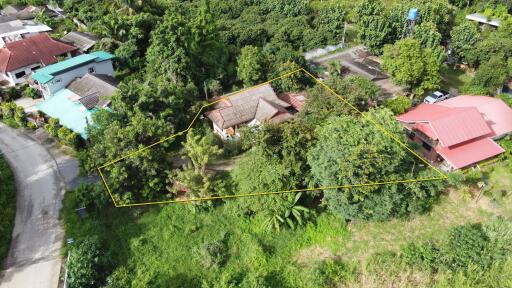 Aerial view of a property plot with surrounding greenery and nearby houses