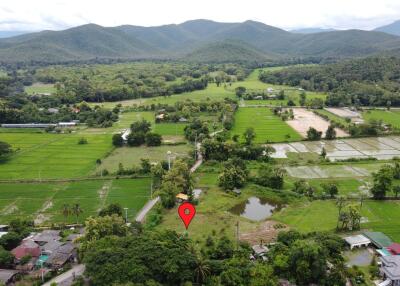 Aerial view of a rural landscape with fields, forested hills, and scattered houses.