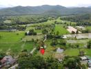 Aerial view of a rural landscape with fields, forested hills, and scattered houses.