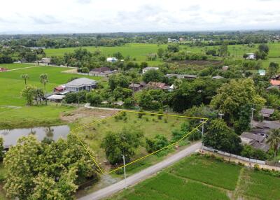 Aerial view of a plot of land with surrounding greenery and houses