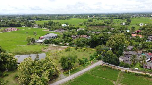 Aerial view of a plot of land with surrounding greenery and houses