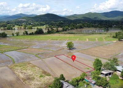 Aerial view of agricultural land with surrounding mountainous landscape.