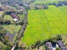 Aerial view of expansive green fields bordered by trees and buildings