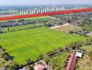 Aerial view of a large green field with a surrounding area in countryside