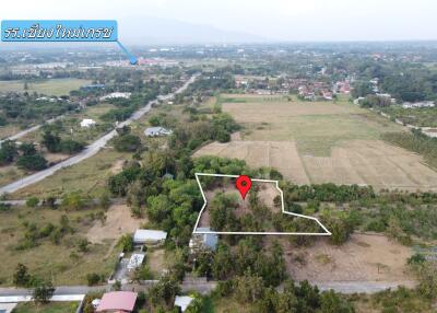 Aerial view of a large plot of land in a rural area with a marker indicating the property location.