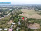 Aerial view of a large plot of land in a rural area with a marker indicating the property location.