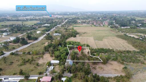 Aerial view of a large plot of land in a rural area with a marker indicating the property location.