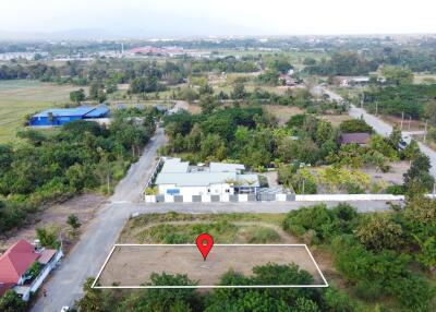 Aerial view of empty plot of land with buildings and greenery in the surrounding area