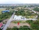 Aerial view of empty plot of land with buildings and greenery in the surrounding area