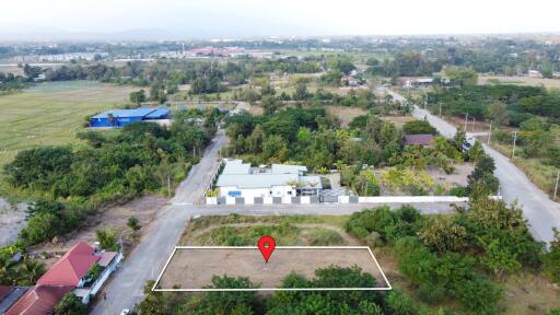 Aerial view of empty plot of land with buildings and greenery in the surrounding area