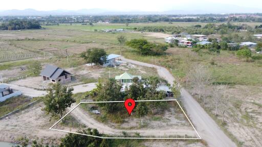 Aerial view of a marked land plot in a rural area with surrounding greenery