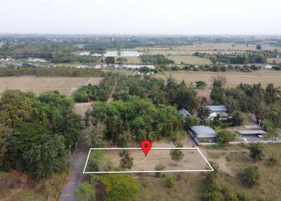 Aerial view of land plot with surrounding greenery and nearby buildings