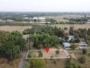 Aerial view of land plot with surrounding greenery and nearby buildings