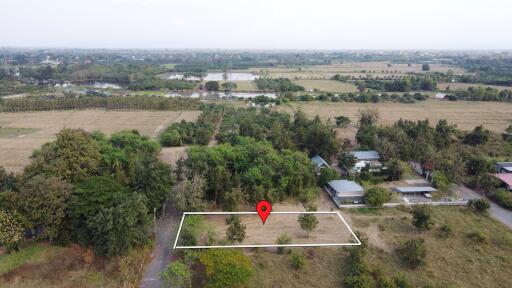 Aerial view of land plot with surrounding greenery and nearby buildings