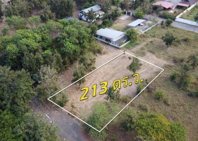 Aerial view of a land plot with surrounding greenery and buildings