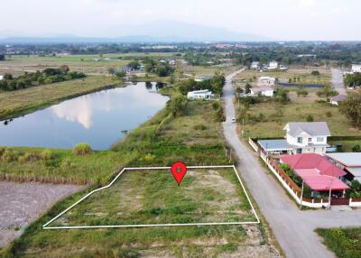 Vacant plot of land next to houses and a body of water