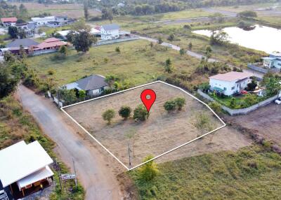 Aerial view of an empty plot of land with a red pin marking its location