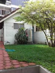 Backyard with greenery, a small annex building, and a water tank