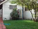 Backyard with greenery, a small annex building, and a water tank