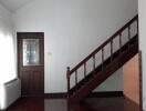 Living room with wooden stairs and door