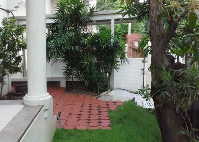 Outdoor garden area with greenery and tiled patio