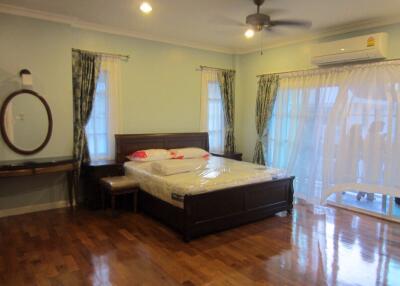 Spacious bedroom with wooden flooring, large windows, air conditioning, and a ceiling fan