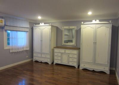 Spacious bedroom with large wooden wardrobes and a dresser with mirror